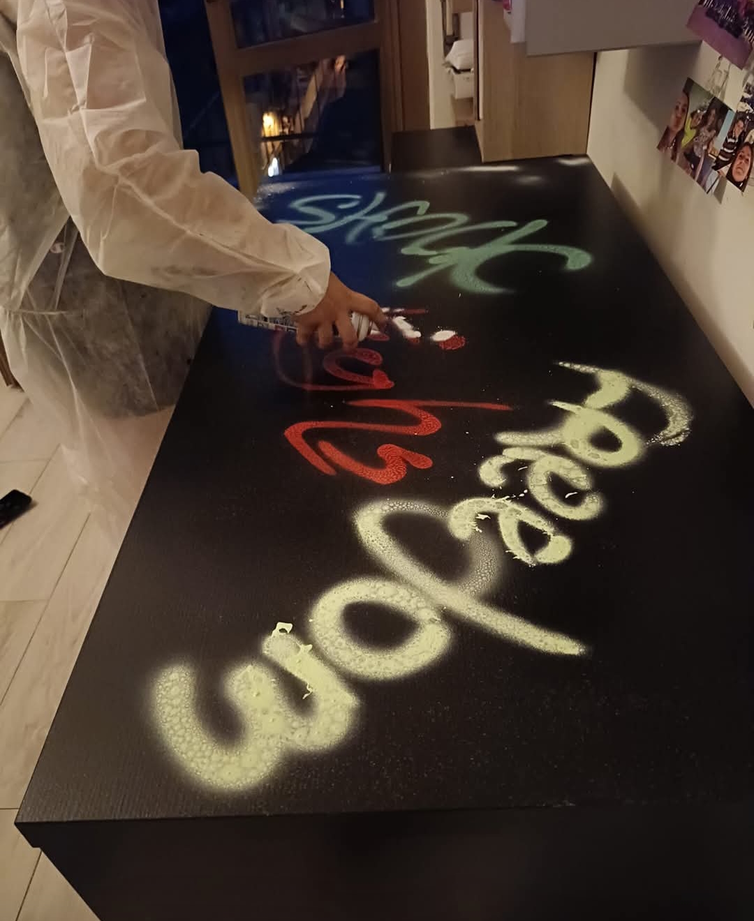 Francesca realizza una scritta artistica con spray su superficie nera